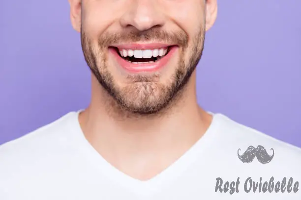 close-up cropped portrait of attractive trendy stylish toothy man with wide beaming smile and healthy teeth over pastel